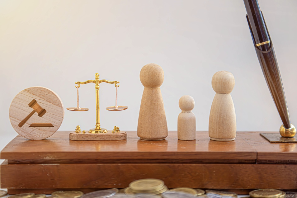 Wooden family figures beside legal symbols and coins.