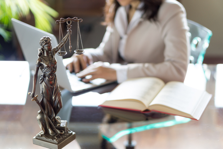 Statue of Justice with scales and lawyer working